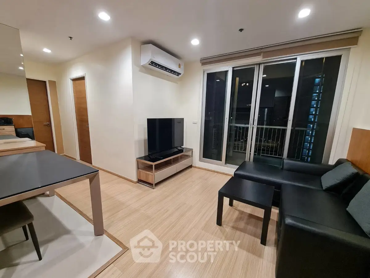 Modern living room with sleek furniture and balcony access in a stylish apartment.