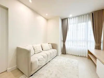 Bright and cozy living room with elegant sofa and large window, perfect for relaxation.