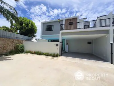 Modern two-story house with spacious driveway and sleek design under a clear blue sky.