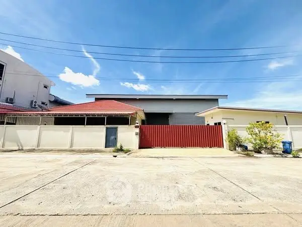 Charming residential property with red roof and spacious driveway under clear blue sky.