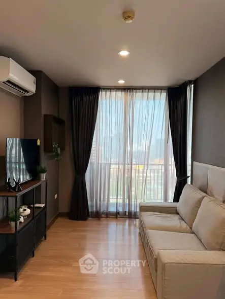 Modern living room with large window and city view, featuring a comfortable sofa and sleek TV stand.