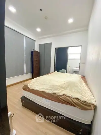 Cozy bedroom with natural light and modern decor, featuring a comfortable bed and sleek flooring.