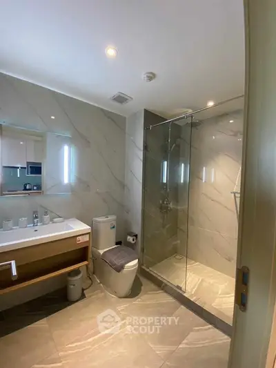 Modern bathroom with glass shower and sleek fixtures in luxury apartment