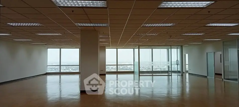 Spacious office space with large windows offering panoramic city views and ample natural light.