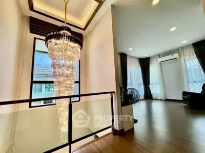 Luxurious interior with elegant chandelier and spacious living area, featuring large windows and modern design.