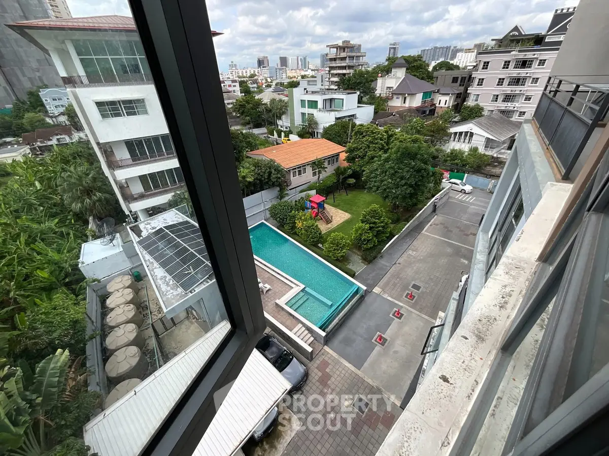 Stunning aerial view of residential area with pool and lush greenery.