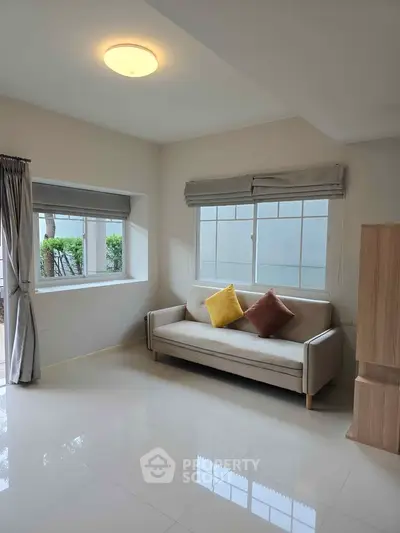 Bright living room with modern sofa and large windows, perfect for relaxation.