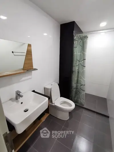 Modern bathroom with sleek design, featuring a shower, toilet, and sink in a contemporary setting.