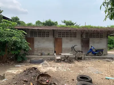 Rustic exterior with motorbike and greenery, showcasing potential for renovation or development.