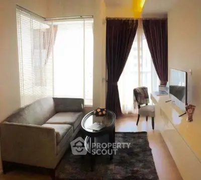 Cozy living room with modern sofa and TV setup, featuring elegant curtains and natural light.