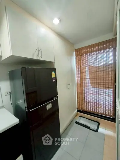 Modern kitchen with sleek black fridge and bamboo blinds, offering a cozy and functional space.