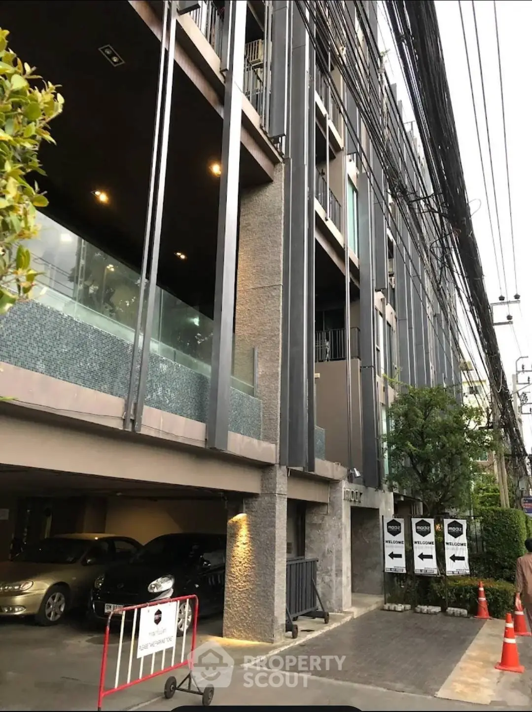 Modern urban building exterior with parking area and sleek architectural design.