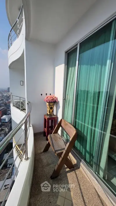 Charming balcony with city view, featuring a cozy chair and decorative flowers, perfect for relaxation.