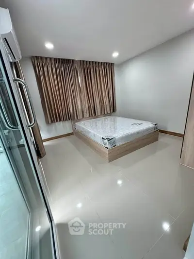 Spacious bedroom with modern design and natural light, featuring a sleek bed and elegant curtains.