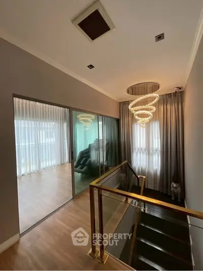 Luxurious staircase with elegant chandelier and floor-to-ceiling windows
