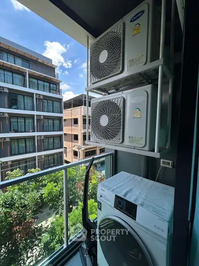 Modern apartment balcony with air conditioning units and washing machine, overlooking urban view.