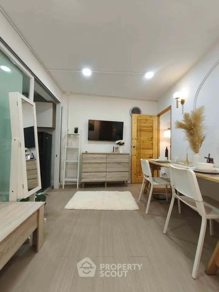 Modern living room with stylish decor and dining area, featuring wooden furniture and ambient lighting.