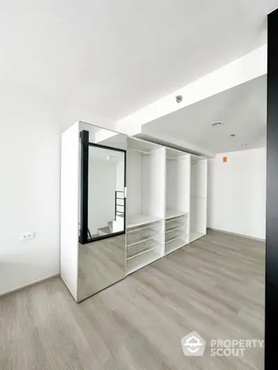 Spacious modern closet with mirrored sliding doors in a bright minimalist room