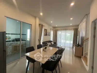 Spacious modern living room with dining area and open kitchen, featuring elegant decor and ample natural light.