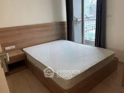 Spacious bedroom with wooden flooring and large window offering city views.