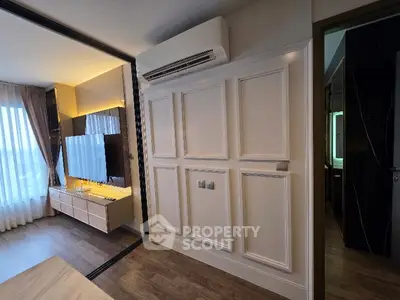 Modern living room with elegant paneling and large TV, featuring stylish wood flooring and natural light.