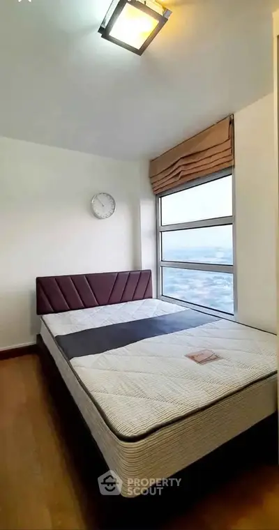Cozy bedroom with large window offering stunning city views, featuring a modern bed and stylish decor.