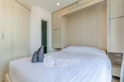 Cozy bedroom with modern wooden cabinetry and neatly made bed in bright apartment.