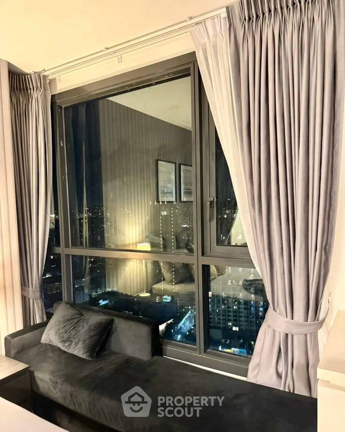 Luxurious high-rise apartment with stunning city view from large window and elegant curtains.