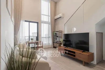 Spacious modern living room with high ceilings and large windows, featuring elegant furniture and a sleek TV setup.