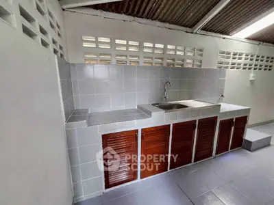 Spacious outdoor kitchen with tiled countertops and wooden cabinets