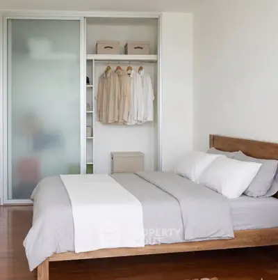 Modern bedroom with wooden bed frame and sliding closet doors in a stylish apartment.