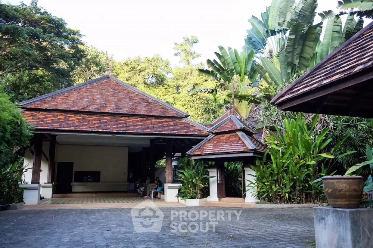 Charming tropical villa entrance with lush greenery and traditional architecture.