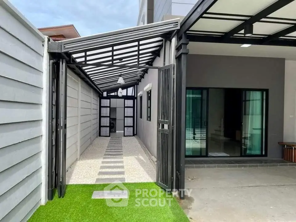 Modern home exterior with sleek design and artificial grass pathway leading to entrance.