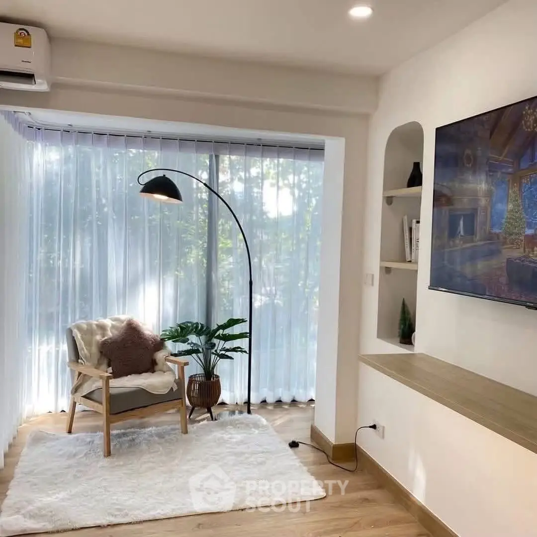 Charming living room with cozy chair, floor lamp, and wall-mounted TV, perfect for relaxation.