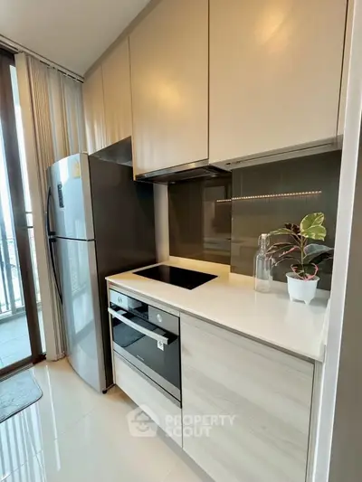 Modern kitchen with sleek cabinets and built-in appliances, featuring a balcony view.
