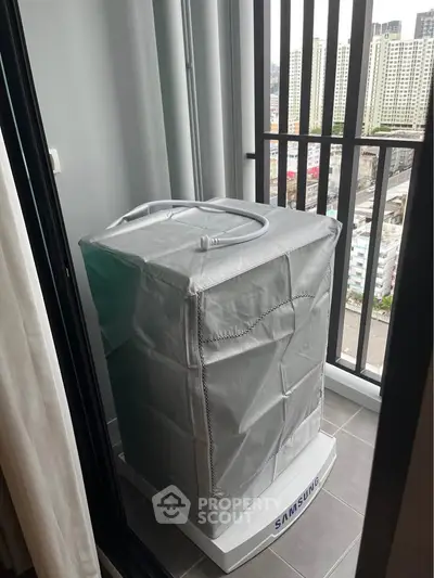 Compact balcony with washing machine and city view, ideal for urban living.