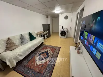 Cozy living room with modern TV setup and washing machine, perfect for entertainment and convenience.
