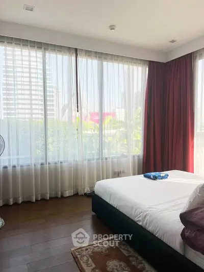 Spacious bedroom with large windows offering city views and natural light.