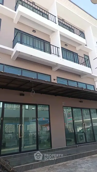 Modern multi-story building with glass balconies and large windows