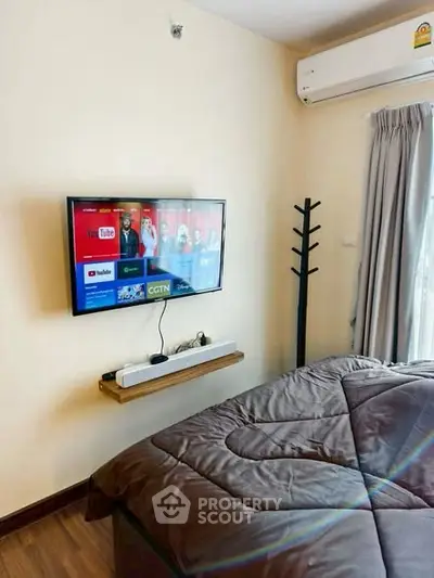 Cozy bedroom with wall-mounted TV and air conditioning, perfect for relaxation.
