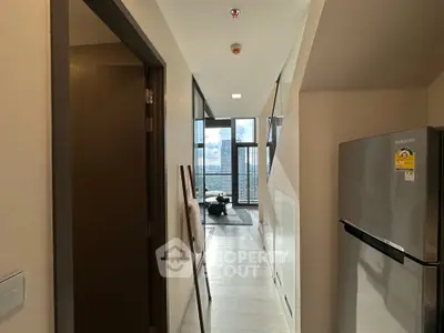 Modern apartment hallway leading to a bright living area with stunning city views.