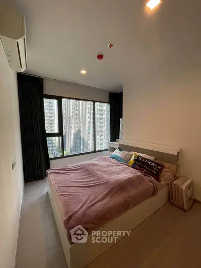 Modern bedroom with large window and city view in high-rise apartment