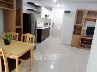 Modern open-layout kitchen and dining area with sleek appliances and wooden furniture.
