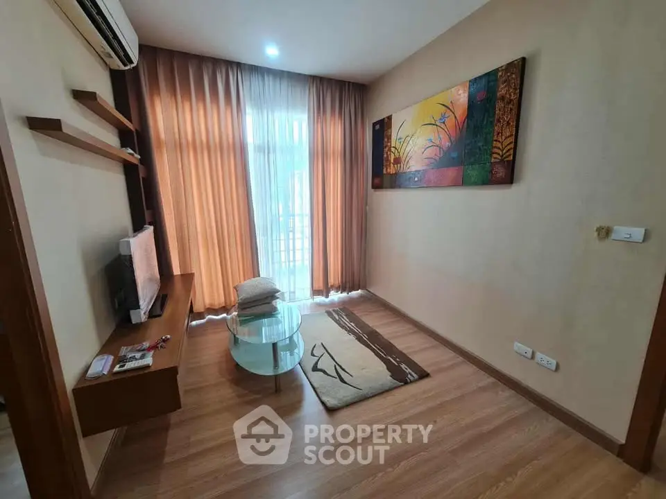 Cozy living room with modern decor, wooden flooring, and natural light from large window.