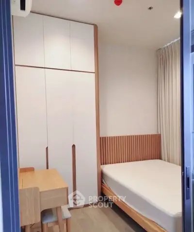 Modern minimalist bedroom with sleek wooden furniture and ample storage space.