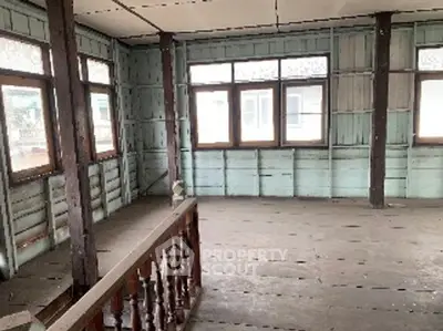 Spacious unfinished room with large windows and wooden flooring, ideal for renovation.