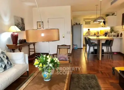 Charming living room with elegant decor and open kitchen layout, featuring stylish lighting and wooden flooring.