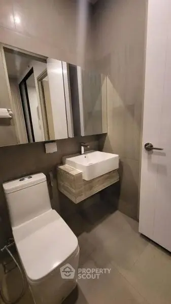 Modern bathroom with sleek fixtures and minimalist design, featuring a wall-mounted sink and contemporary toilet.