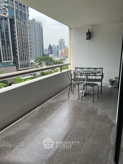Spacious balcony with city view and elegant outdoor seating in modern high-rise building.
