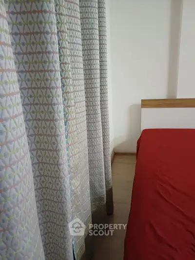 Cozy bedroom with vibrant red bedding and patterned curtains